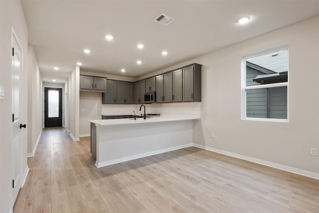 727 Palo Brea Loop, Hutto, TX 78634 - kitchen with stainless steel microwave, a peninsula, light wood-style flooring, light countertops, and baseboards