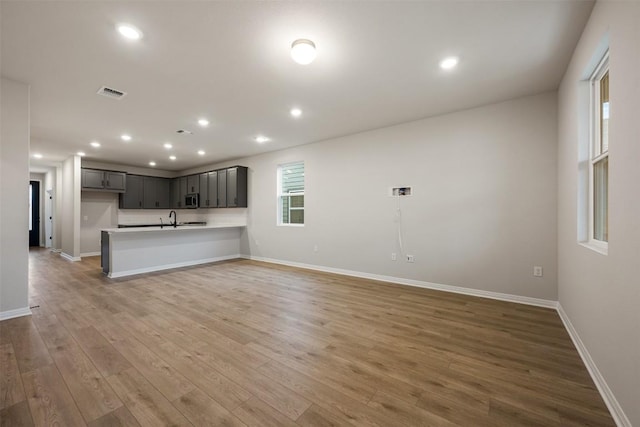 727 Palo Brea Loop, Hutto, TX 78634 - unfurnished living room featuring light wood-style floors, baseboards, a sink, and recessed lighting