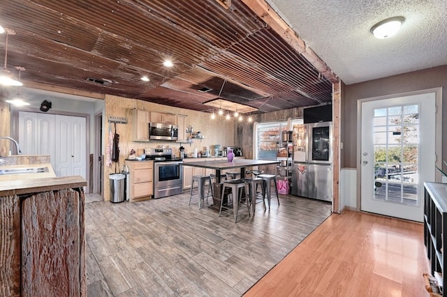 interior space with sink, light brown cabinets, light hardwood / wood-style flooring, a breakfast bar, and appliances with stainless steel finishes