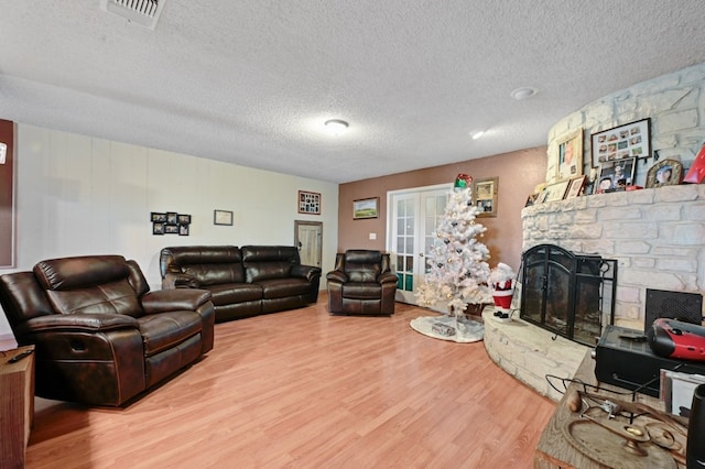 living room with a fireplace, wood-type flooring, a textured ceiling, and french doors