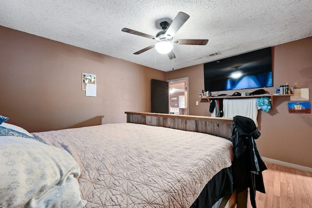 bedroom featuring ceiling fan, wood-type flooring, and a textured ceiling