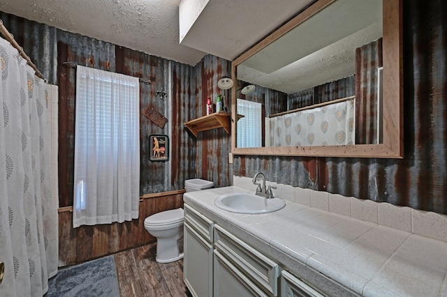 bathroom featuring toilet, vanity, a textured ceiling, and hardwood / wood-style flooring