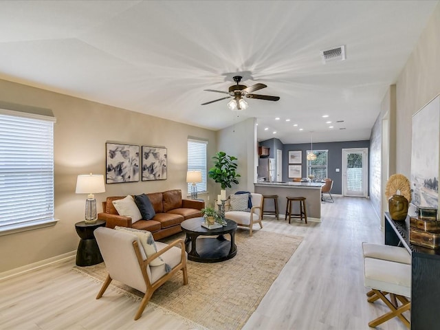 living room with light hardwood / wood-style floors, ceiling fan, and lofted ceiling