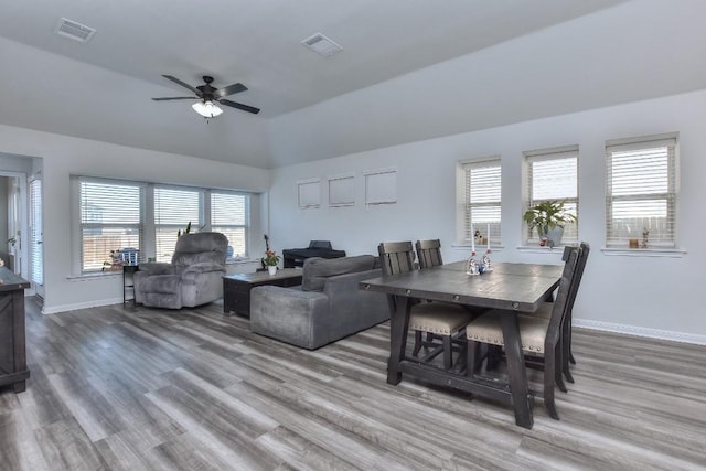 dining space featuring ceiling fan, wood-type flooring, and lofted ceiling