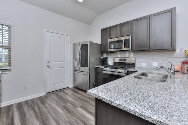 kitchen with sink, dark brown cabinets, stainless steel appliances, and light stone countertops