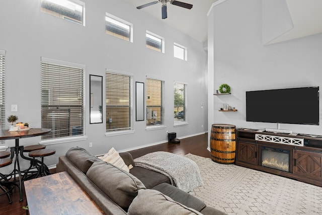 living room featuring a high ceiling, dark hardwood / wood-style flooring, and ceiling fan