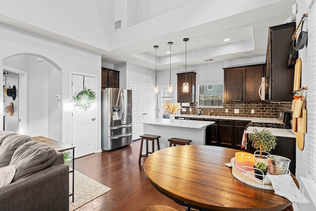 dining area with a tray ceiling, a towering ceiling, and dark wood-type flooring