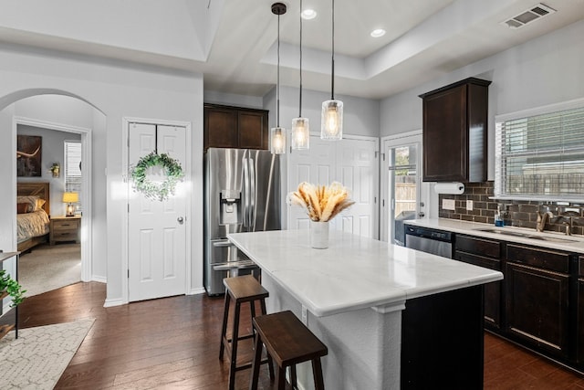 kitchen featuring backsplash, a center island, a kitchen bar, and stainless steel appliances