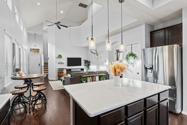 kitchen with stainless steel fridge, a center island, high vaulted ceiling, and dark brown cabinets