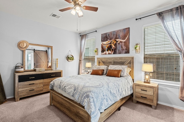 carpeted bedroom featuring a barn door and ceiling fan