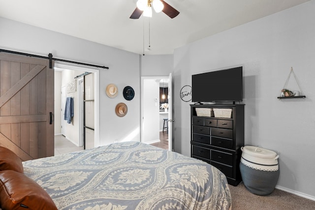 carpeted bedroom featuring a barn door and ceiling fan