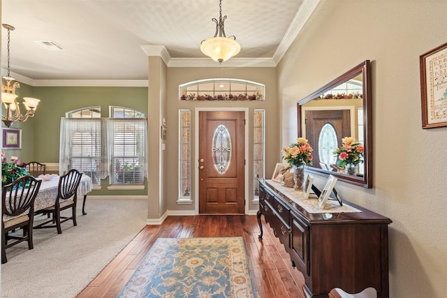 foyer with crown molding, dark wood-type flooring, and an inviting chandelier