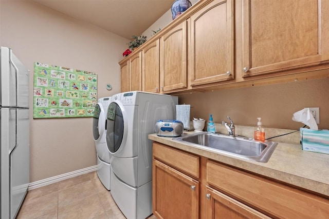 clothes washing area featuring cabinets, light tile patterned floors, sink, and washing machine and clothes dryer