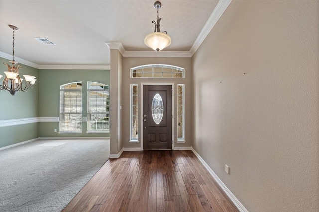 entryway featuring crown molding, dark wood-type flooring, and an inviting chandelier