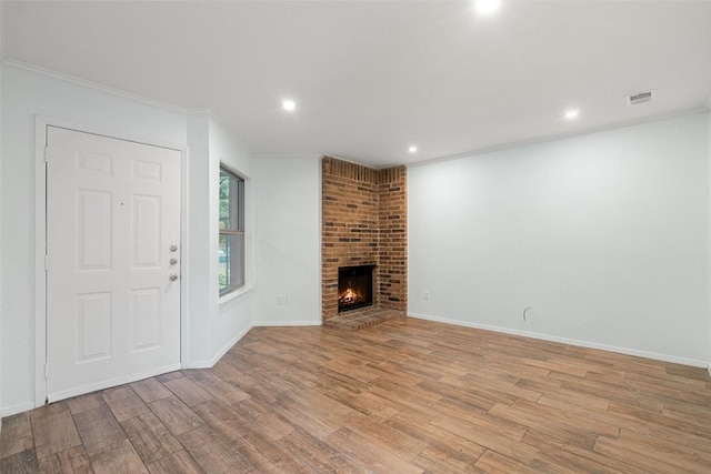 unfurnished living room featuring crown molding, a fireplace, and light wood-type flooring