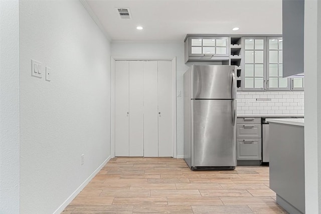 kitchen featuring gray cabinetry, light hardwood / wood-style floors, backsplash, and stainless steel refrigerator