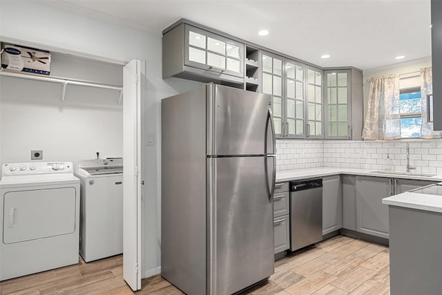 kitchen featuring appliances with stainless steel finishes, gray cabinetry, sink, separate washer and dryer, and light hardwood / wood-style flooring