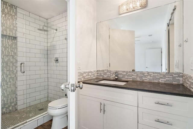 bathroom with vanity, tasteful backsplash, toilet, and a shower with shower door