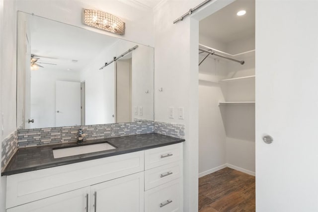 bathroom featuring vanity, crown molding, hardwood / wood-style flooring, decorative backsplash, and ceiling fan