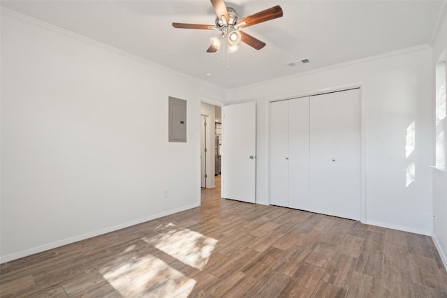 unfurnished bedroom featuring ornamental molding, ceiling fan, wood-type flooring, electric panel, and a closet