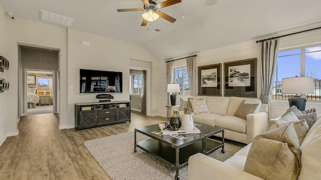 living room featuring ceiling fan, lofted ceiling, and light hardwood / wood-style flooring