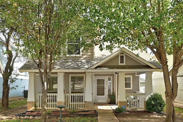 view of front of home featuring central air condition unit, covered porch, and a shingled roof