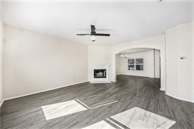 unfurnished living room with ceiling fan with notable chandelier and dark hardwood / wood-style floors