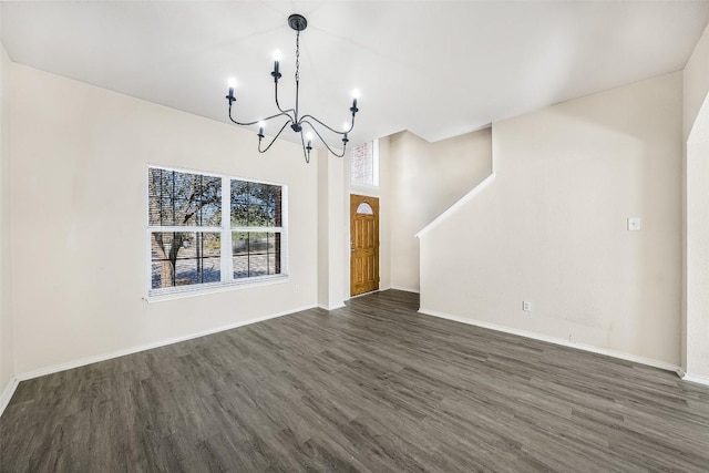 unfurnished living room with dark wood-type flooring and an inviting chandelier