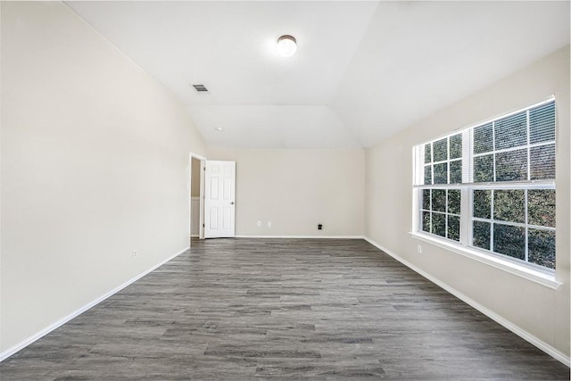 spare room featuring dark hardwood / wood-style flooring and lofted ceiling