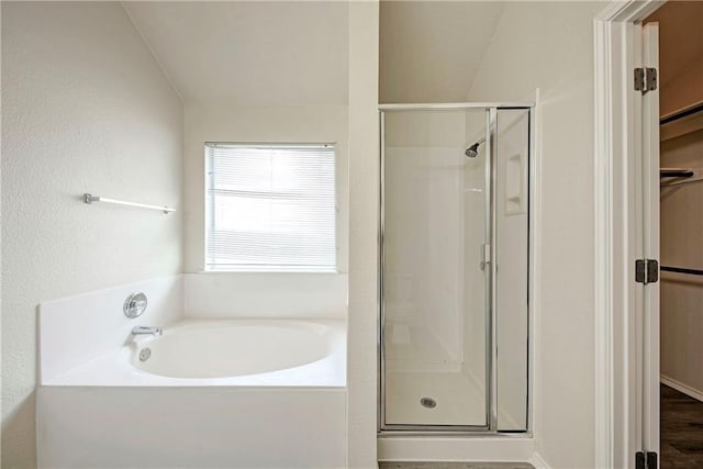 bathroom featuring wood-type flooring, shower with separate bathtub, and vaulted ceiling