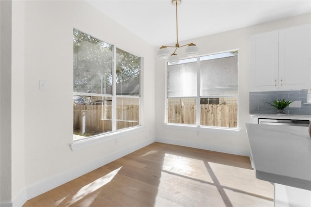 unfurnished dining area with a chandelier and light hardwood / wood-style flooring