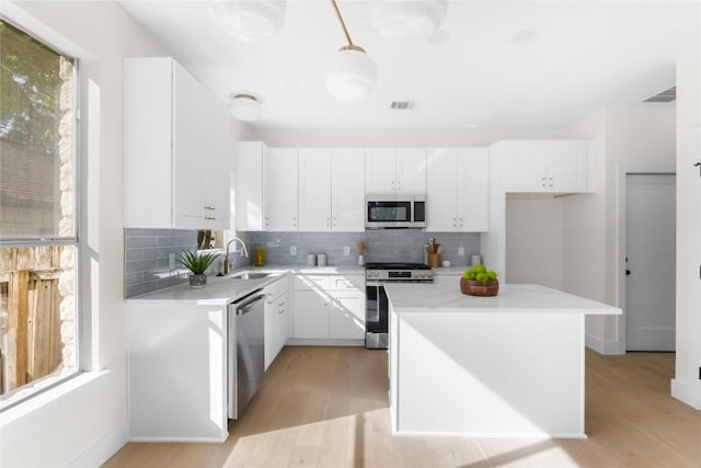 kitchen with sink, white cabinets, light hardwood / wood-style flooring, and appliances with stainless steel finishes