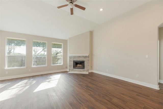 unfurnished living room featuring a stone fireplace, ceiling fan, dark hardwood / wood-style flooring, and vaulted ceiling