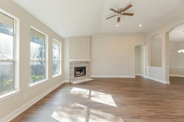 unfurnished living room featuring plenty of natural light, ceiling fan, dark hardwood / wood-style flooring, and a fireplace