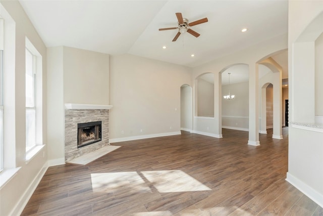 unfurnished living room with hardwood / wood-style flooring, ceiling fan with notable chandelier, and a fireplace