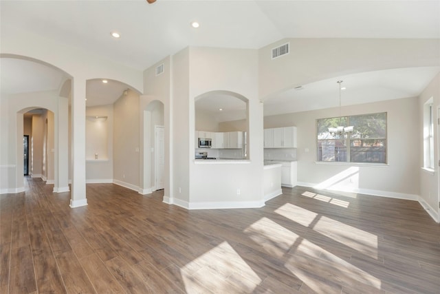 unfurnished living room with lofted ceiling, dark wood-type flooring, and a chandelier