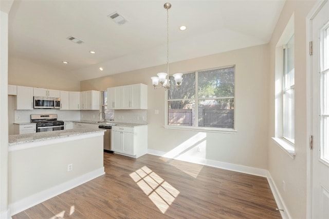 kitchen with stainless steel appliances, vaulted ceiling, wood-type flooring, decorative light fixtures, and white cabinets