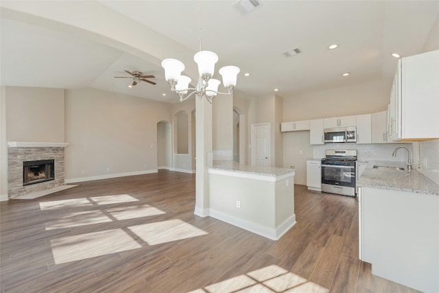 kitchen featuring light stone countertops, hanging light fixtures, appliances with stainless steel finishes, white cabinets, and light wood-type flooring