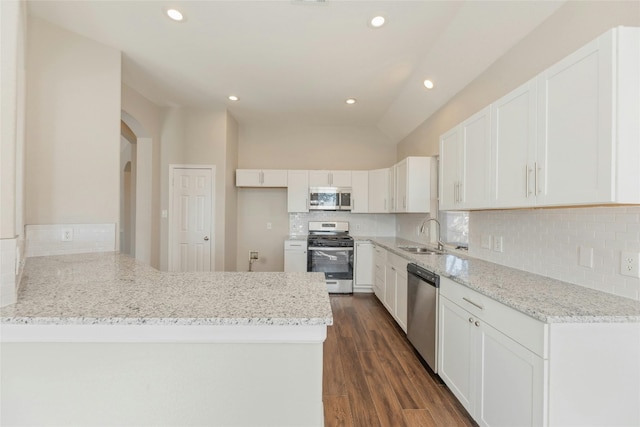 kitchen featuring backsplash, dark wood-type flooring, white cabinets, appliances with stainless steel finishes, and kitchen peninsula