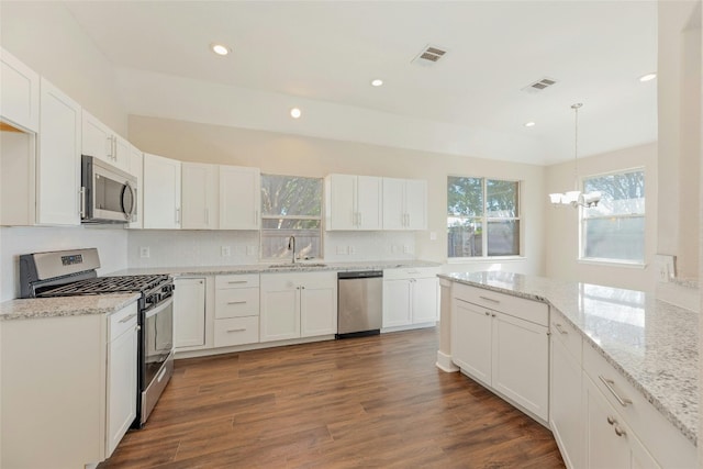 kitchen with pendant lighting, dark hardwood / wood-style floors, white cabinetry, and appliances with stainless steel finishes