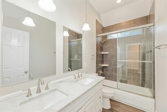 full bathroom with combined bath / shower with glass door, wood-type flooring, vaulted ceiling, toilet, and vanity