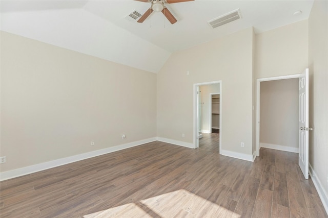 unfurnished bedroom featuring ceiling fan, a spacious closet, dark hardwood / wood-style flooring, vaulted ceiling, and a closet