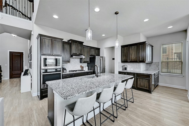 kitchen with appliances with stainless steel finishes, a center island with sink, backsplash, and sink