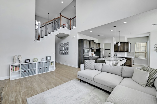 living room featuring a towering ceiling, light hardwood / wood-style flooring, and sink