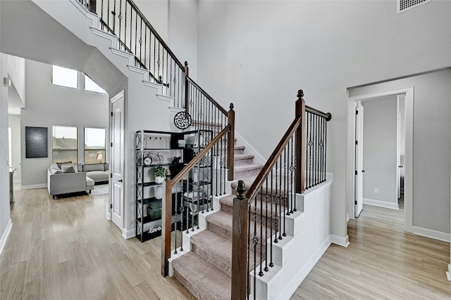 stairs featuring a towering ceiling and hardwood / wood-style flooring