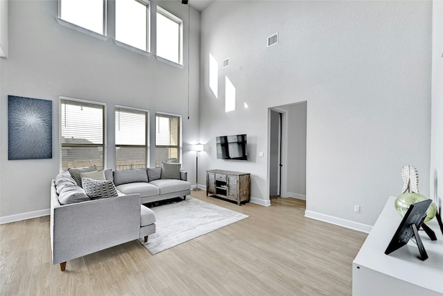 living room featuring a towering ceiling and light wood-type flooring