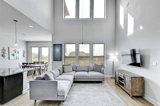 living room featuring a high ceiling, light wood-type flooring, and a wealth of natural light