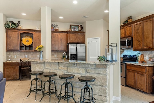 kitchen featuring a kitchen bar, light stone countertops, and stainless steel appliances