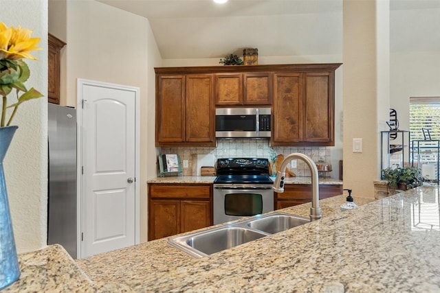 kitchen with light stone countertops, appliances with stainless steel finishes, tasteful backsplash, and vaulted ceiling