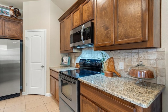 kitchen with decorative backsplash, light stone counters, light tile patterned floors, and stainless steel appliances